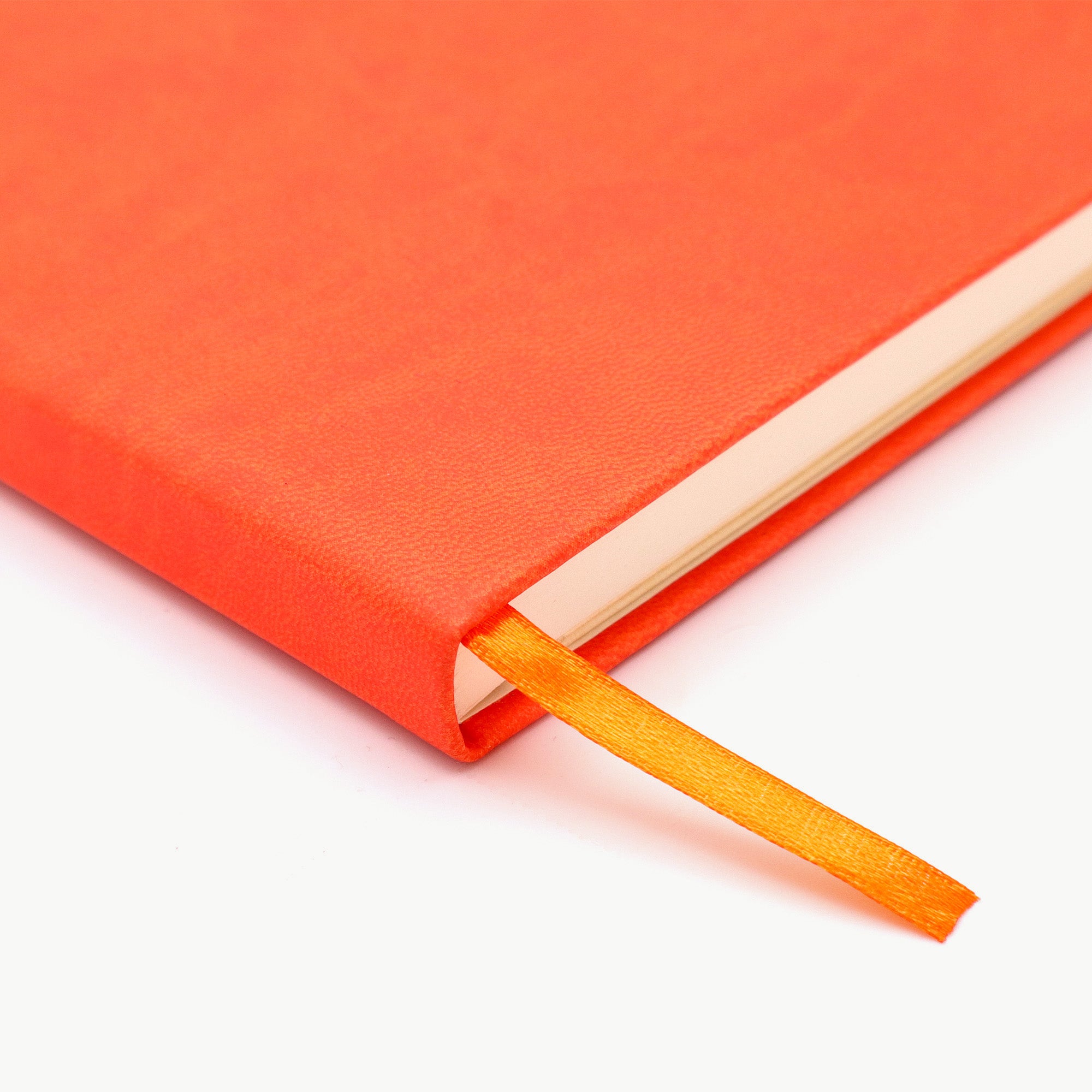 Close-up of an orange notebook with a matching ribbon on a white background